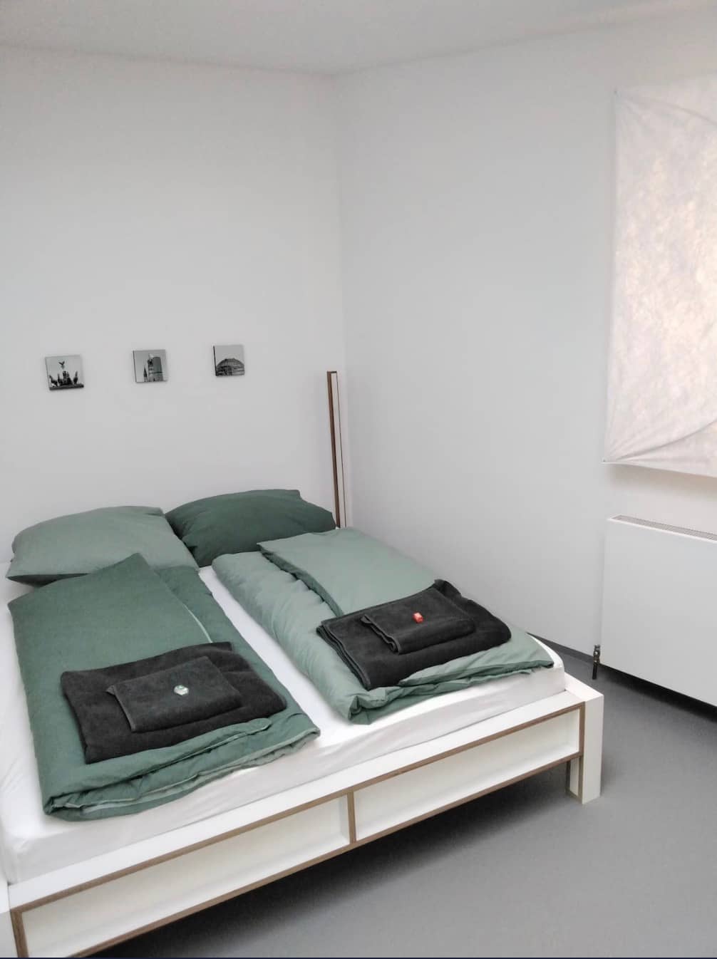 Schlafzimmer mit Doppelbett und salbeigrüner Bettwäsche